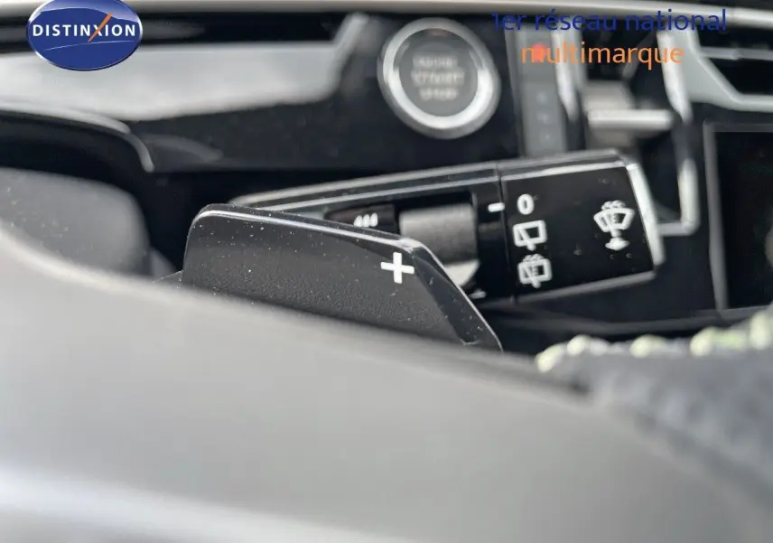 Gros plan sur la palette de changement de vitesse + du Peugeot 5008 Hybrid 136ch GT, intérieur noir et commandes au volant.