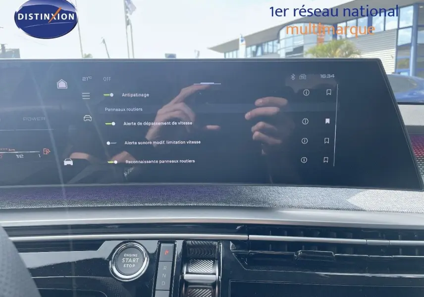 Vue intérieure du tableau de bord du Peugeot 5008 Hybrid 2025 avec écran tactile et bouton start/stop visible.
