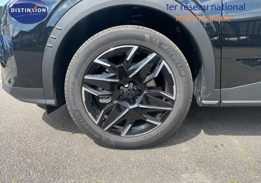 Gros plan sur la roue avant gauche noire perle métal du Peugeot 5008 Hybrid 136ch GT avec jante alliage bicolore.