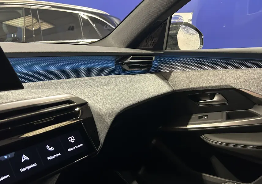 Vue intérieure côté passager du tableau de bord et de la porte d’une Peugeot 3008 gris Artense avec éclairage d’ambiance bleu.