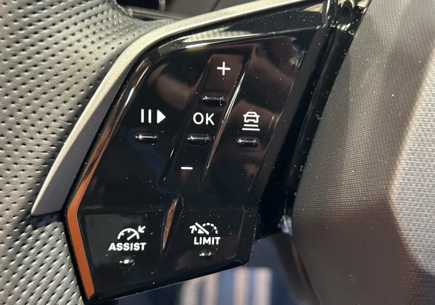 Gros plan sur les commandes noires du volant du Peugeot 3008 gris Artense, avec boutons de régulateur et assistance.