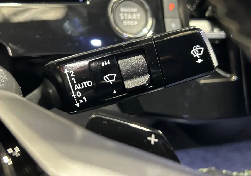 Gros plan sur la commande des essuie-glaces et le bouton start/stop dans l’habitacle noir du Peugeot 3008 gris Artense.