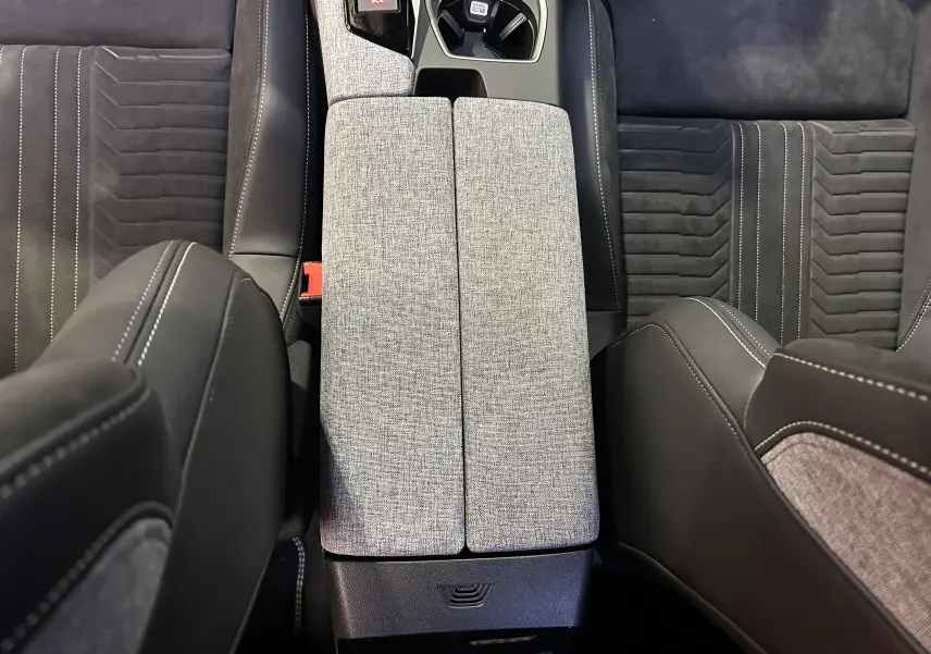 Vue plongeante sur la console centrale tissu gris clair et sièges Alcantara noirs avec surpiqûres blanches du Peugeot 3008 Hybrid 2025.