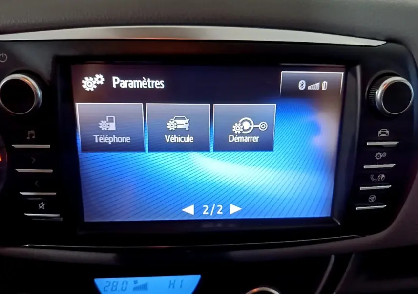 Écran tactile central de la Toyota Yaris blanche 2020 affichant le menu paramètres avec options téléphone, véhicule et démarrer.