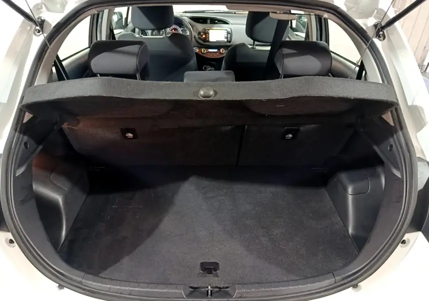 Coffre ouvert d’une Toyota Yaris blanche 2020, vue arrière, banquette arrière et tableau de bord visibles.