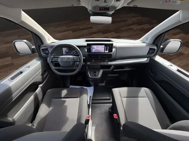 Vue intérieure avant du Citroën Jumpy 2026, tableau de bord gris avec écran tactile et sièges tissu bi-ton noir-gris.