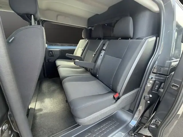 Vue intérieure côté droit des sièges arrière gris foncé du Citroën Jumpy 2026 avec habillage bois et porte latérale ouverte.