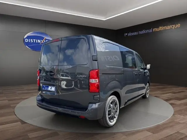 Vue 3/4 arrière droite du Citroën Jumpy gris titane avec jantes noires et bouclier arrière partiellement peint.