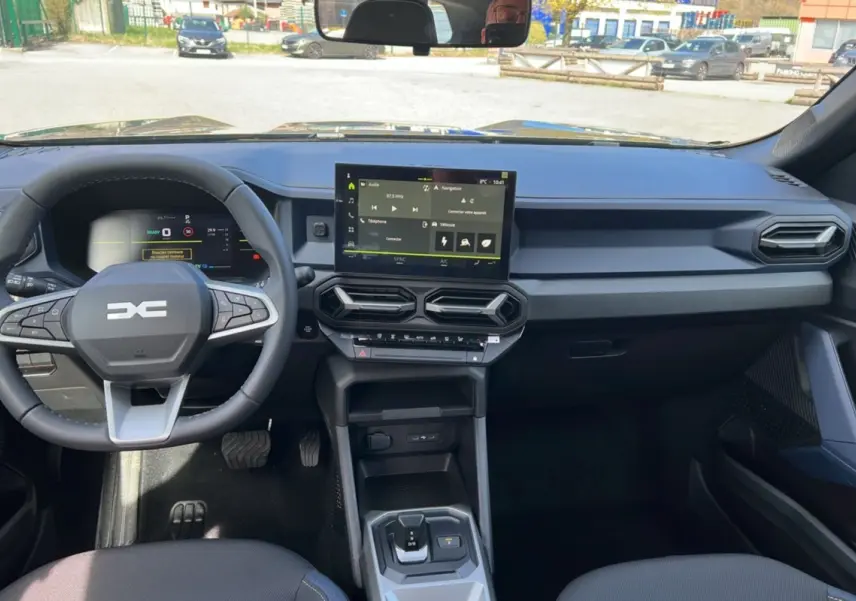 Vue intérieure avant du tableau de bord et volant cuir du Dacia Bigster Hybrid 155 Expression Plus, avec écran tactile central.