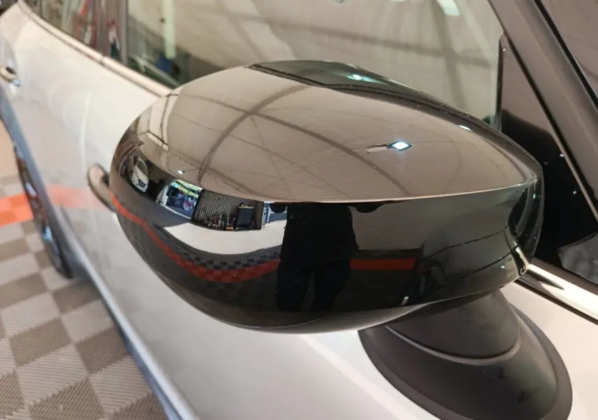 Rétroviseur noir brillant côté gauche d'une MINI Countryman gris foncé, vue rapprochée en intérieur.