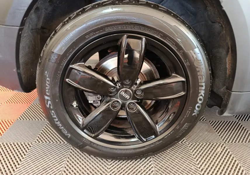 Gros plan sur la jante noire brillante en cinq branches du MINI Countryman gris foncé, avec pneu Hankook visible.