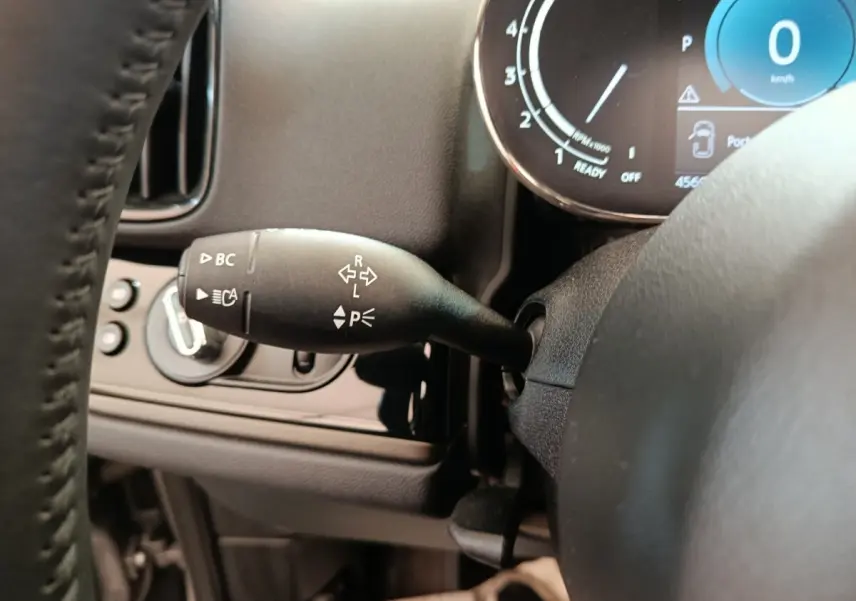 Gros plan sur la commande de clignotants à gauche du volant du MINI Countryman gris foncé, avec tableau de bord digital visible.