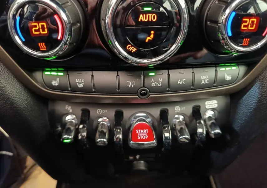 Gros plan sur la console centrale du MINI Countryman 2023, boutons chromés et bouton rouge Start Engine Stop.