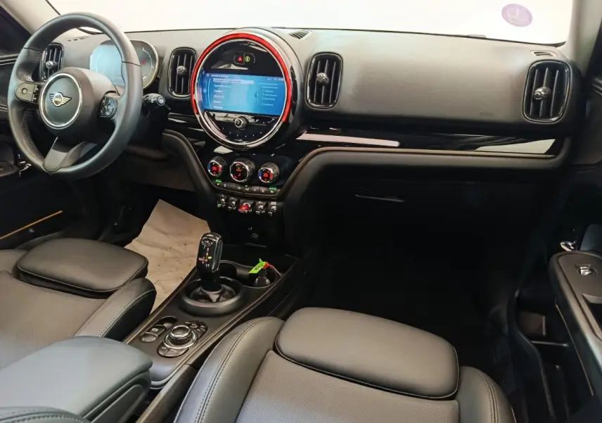 Vue intérieure avant droite du tableau de bord noir et écran tactile circulaire avec éclairage rouge du MINI Countryman 2023.