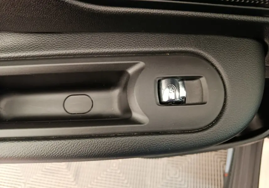 Gros plan sur la commande de verrouillage des portes côté conducteur, finition noire mate et chrome, MINI Countryman gris foncé.