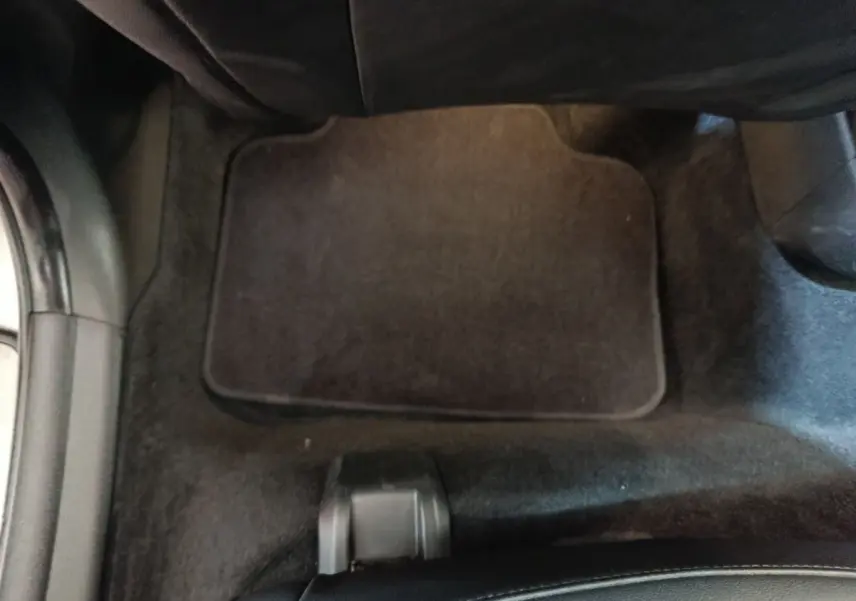 Vue intérieure du plancher côté passager avec tapis noir et partie inférieure du siège MINI Countryman gris foncé.