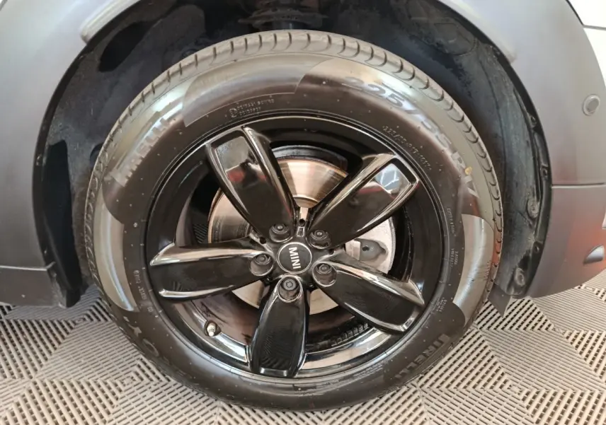 Gros plan sur la jante noire brillante et le pneu Pirelli d’un MINI Countryman gris foncé, côté avant droit.