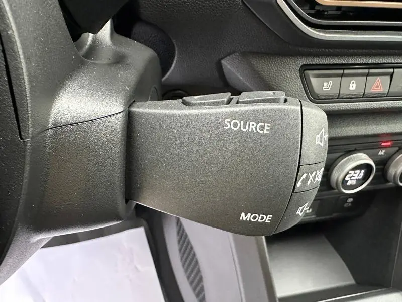 Gros plan sur la commande audio au volant du Dacia Jogger 2024, intérieur noir avec boutons source et mode visibles.