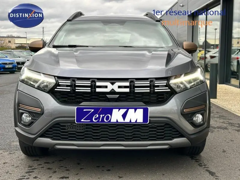 Vue frontale d'un Dacia Jogger gris schiste métallisé avec calandre noire et feux LED allumés.