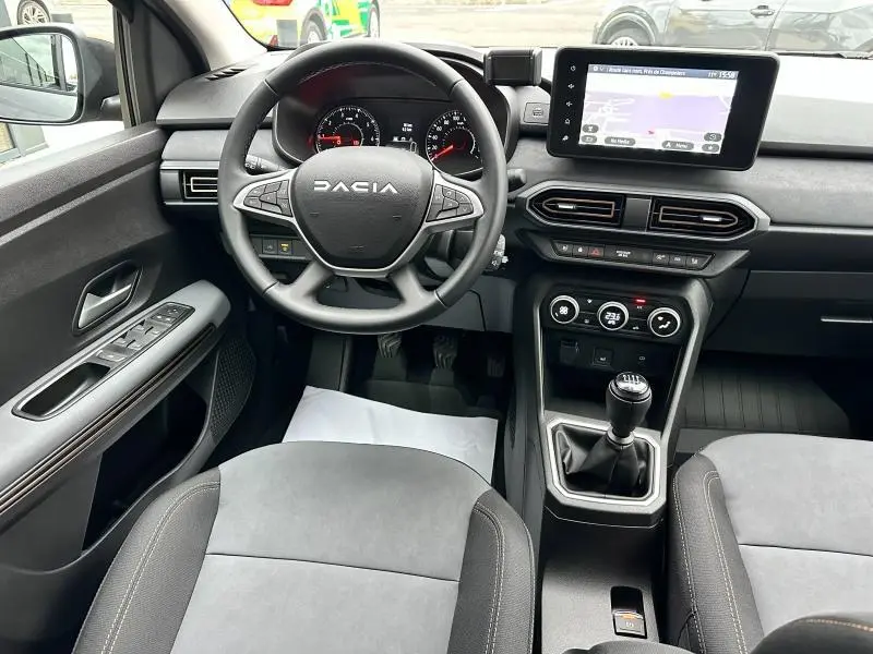 Vue intérieure avant du tableau de bord et volant du Dacia Jogger gris, avec écran tactile et boîte manuelle.