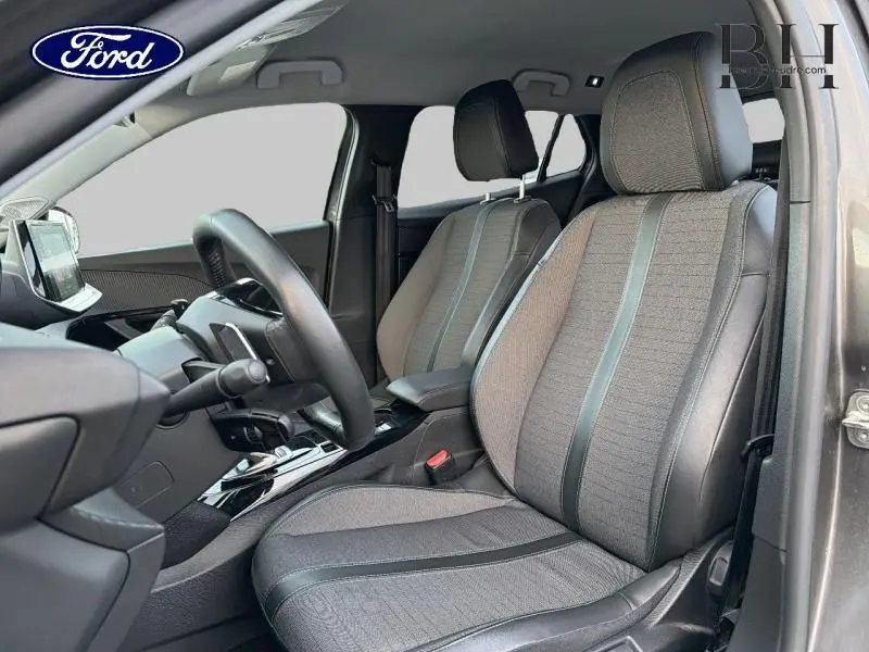 Vue intérieure côté conducteur du Peugeot 2008 gris Artense, mettant en valeur les sièges tissu tri-matière et le volant multifonction.