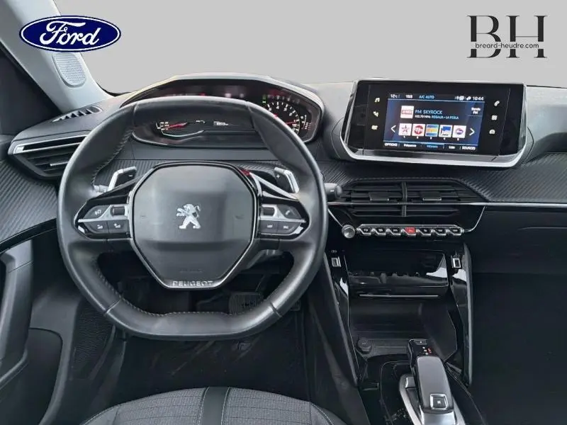 Intérieur Peugeot 2008 2021 vu de face, volant compact, écran tactile i-Cockpit 3D et console centrale noire brillante.