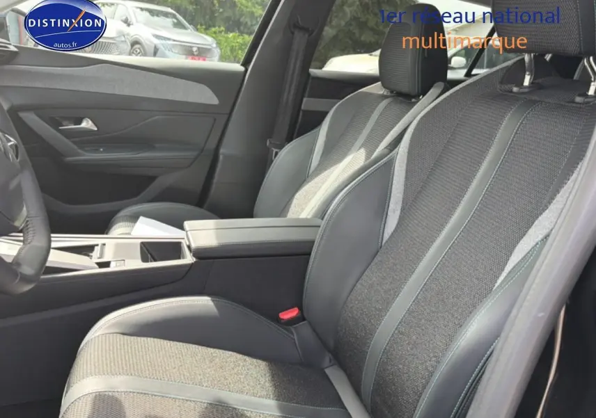 Vue intérieure côté droit montrant les sièges avant en tissu et cuir avec accoudoir central de la Peugeot 408 noire 2024.