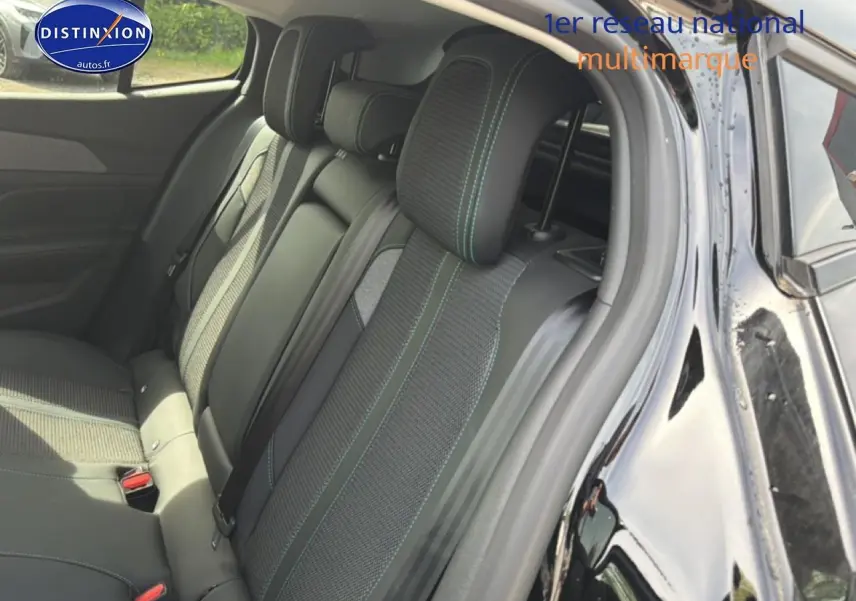 Vue intérieure côté arrière droit montrant la banquette arrière noire avec surpiqûres vertes du Peugeot 408 Hybrid 136 allure e-dcs6 2024.