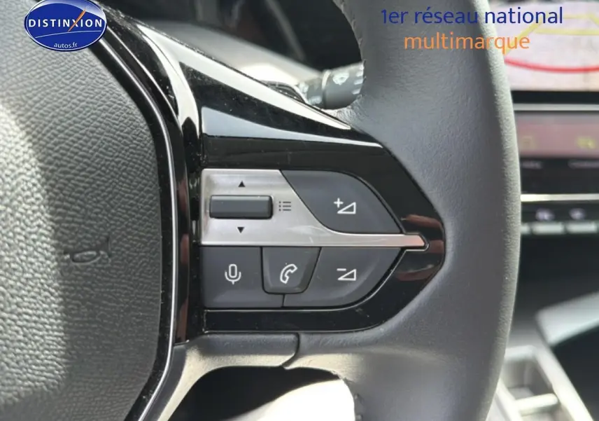 Gros plan sur les commandes gauche du volant cuir noir du Peugeot 408 Hybrid 2024 avec écran tactile en arrière-plan.
