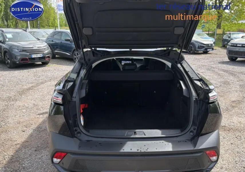 Vue arrière du coffre ouvert d'une Peugeot 408 Hybrid 136 allure e-dcs6 noire, stationnée sur un parking extérieur.