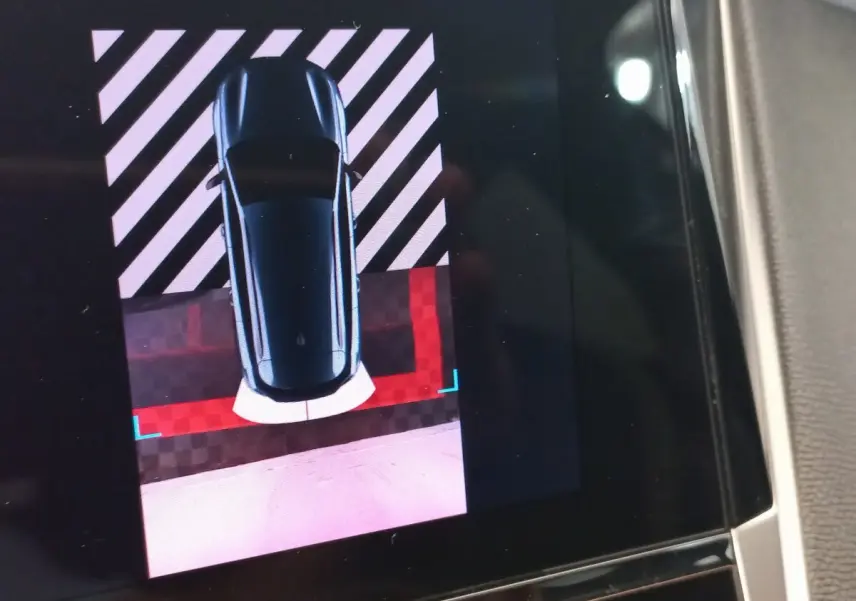 Vue écran intérieur montrant la Peugeot 308 bleue en caméra de recul avec repères de stationnement rouges et blancs.