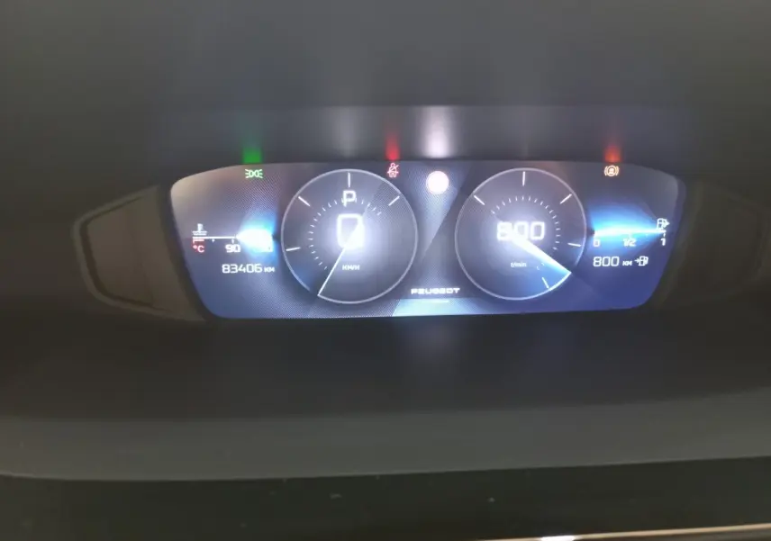 Tableau de bord numérique de Peugeot 308 bleu, affichant vitesse, compte-tours et jauges, vue frontale rapprochée.
