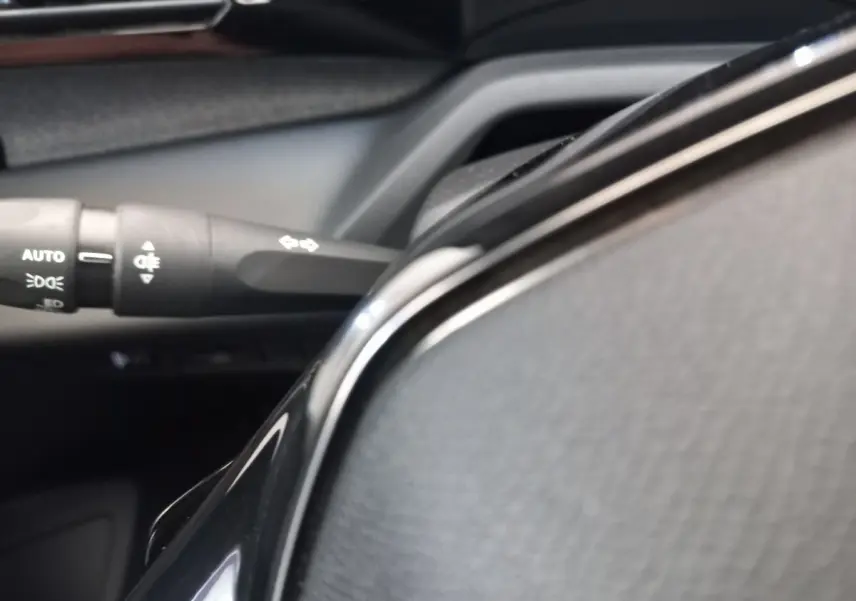 Gros plan sur le volant cuir noir multifonctions et la commande des feux dans l’habitacle d’une Peugeot 308.