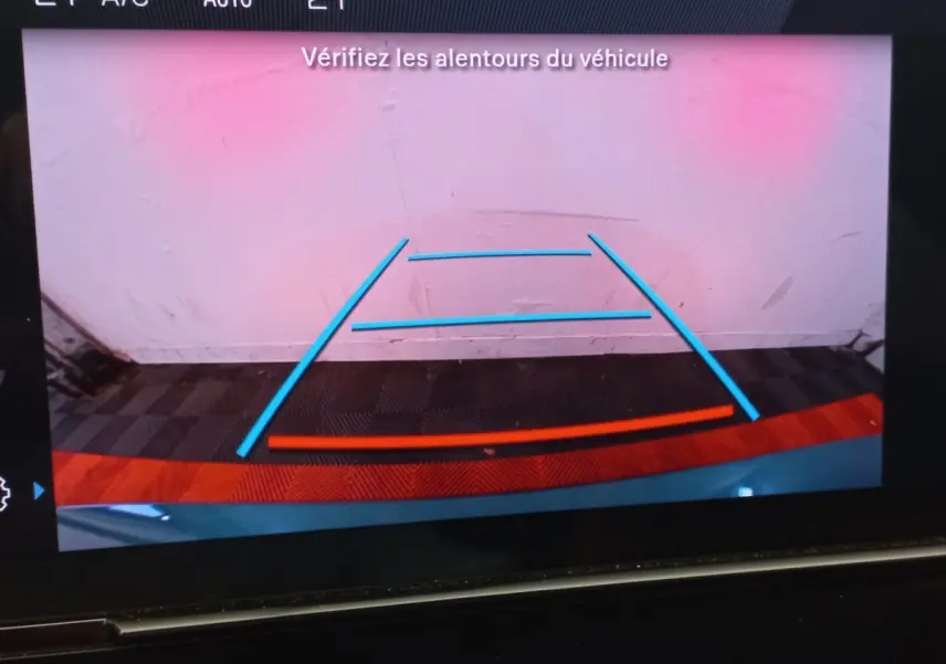 Vue écran caméra de recul d'une Peugeot 308 bleu, avec lignes de guidage bleues et rouges visibles.