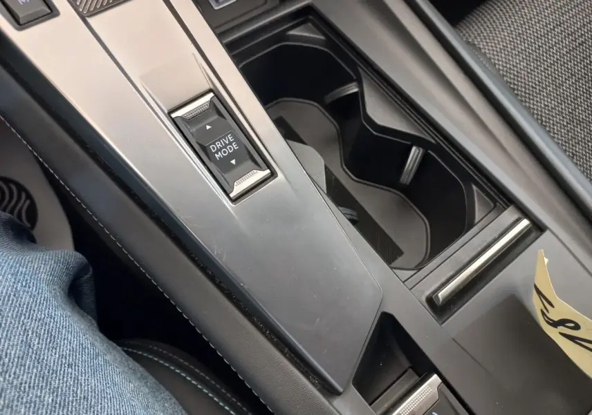 Vue rapprochée de la console centrale noire de la Peugeot 308 bleu, avec bouton Drive Mode et frein à main électrique.