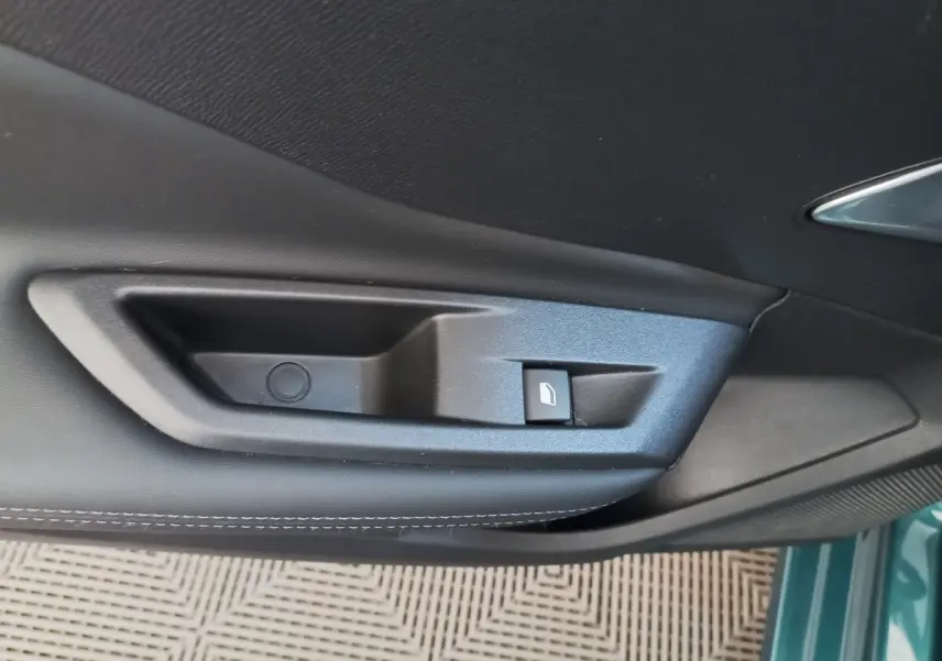Poignée intérieure de porte côté gauche en plastique noir sur Peugeot 308 bleu, vue rapprochée.