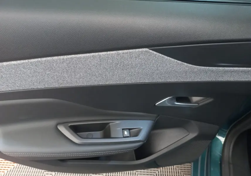 Vue intérieure côté gauche de la porte avant d'une Peugeot 308 bleu, avec poignée argentée et commande de verrouillage.