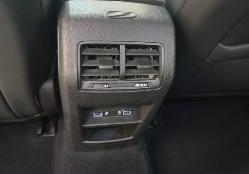 Gros plan sur la console arrière noire de la Peugeot 308 avec bouches d’aération et ports USB visibles.