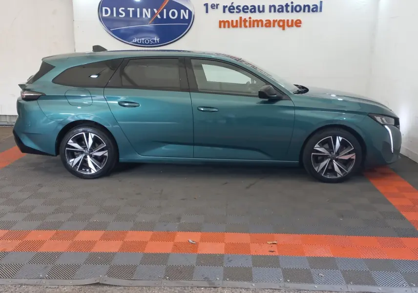 Vue de profil côté gauche d'une Peugeot 308 break bleu métallisé, avec jantes alliage et vitres teintées.