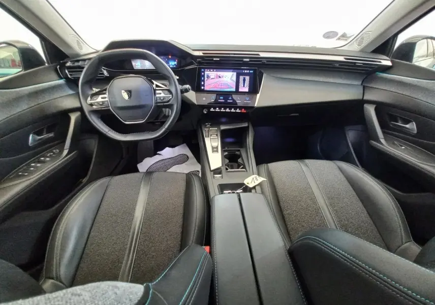Vue intérieure avant de la Peugeot 308 PureTech 130 bleu, avec volant cuir multifonctions et écran tactile central.