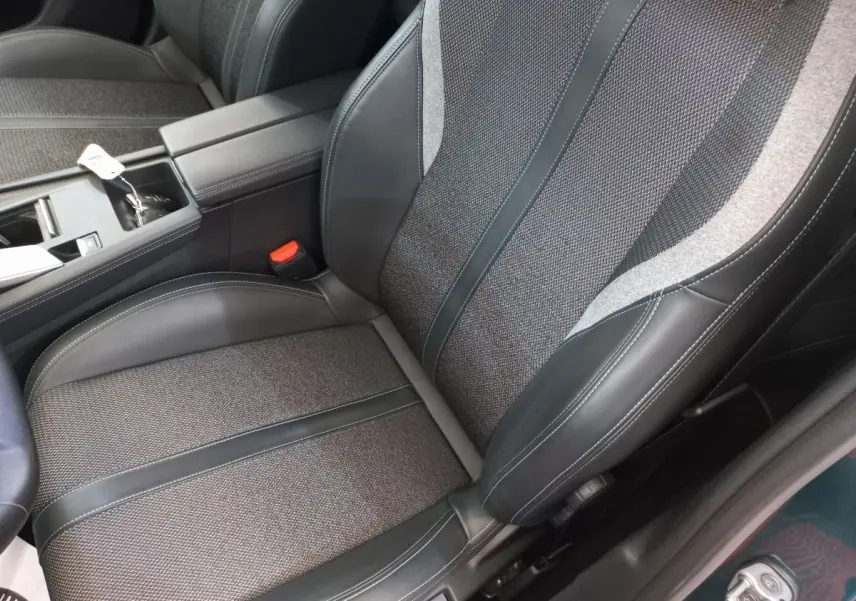 Gros plan sur le siège avant droit en tissu et cuir noir de la Peugeot 308 bleu, avec accoudoir central visible.