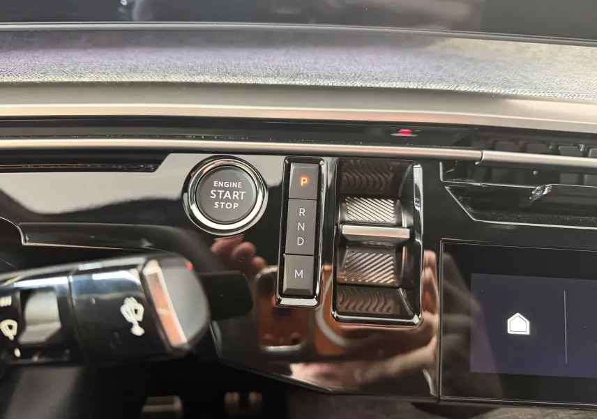 Détail intérieur du tableau de bord du Peugeot 3008 Hybrid 145 GT, avec bouton start/stop et sélecteur de vitesses.
