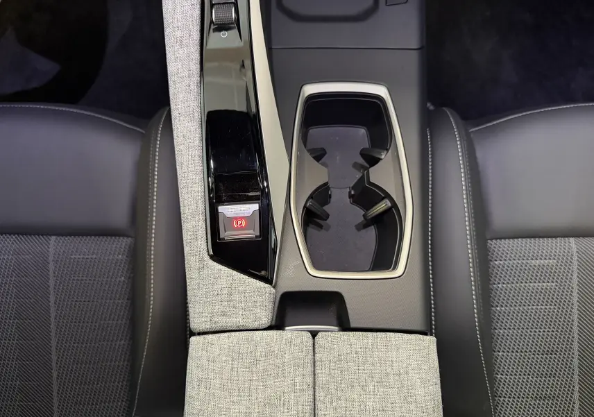 Vue plongeante sur la console centrale du Peugeot 3008 Hybrid 145 GT, avec accoudoirs tissu gris et sièges noirs.