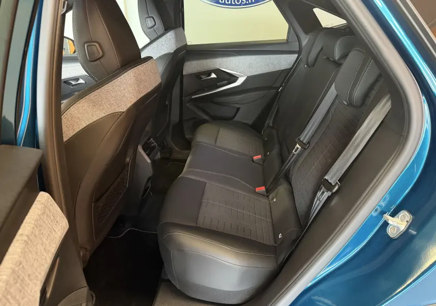 Vue intérieure côté gauche des sièges arrière du Peugeot 3008 Hybrid 145 GT bleu Obsession avec sellerie tissu embossé et surpiqûres claires.