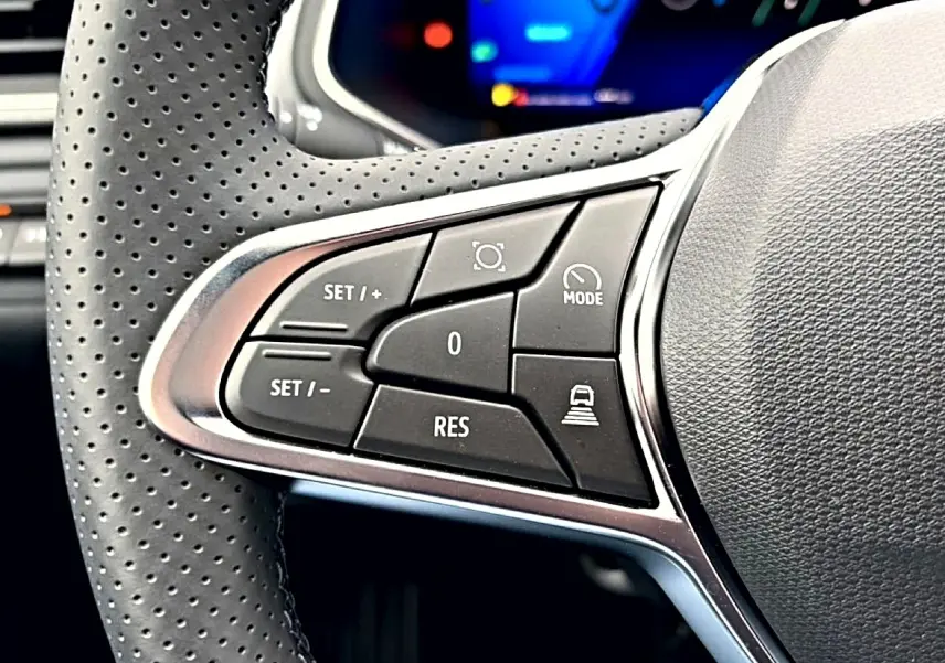Gros plan sur les commandes de régulateur de vitesse au volant perforé du Renault Symbioz bleu mercure, intérieur moderne.