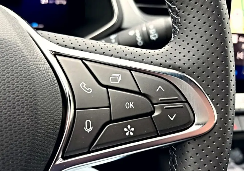 Gros plan sur les commandes multifonctions noires et argentées du volant perforé du Renault Symbioz bleu mercure.
