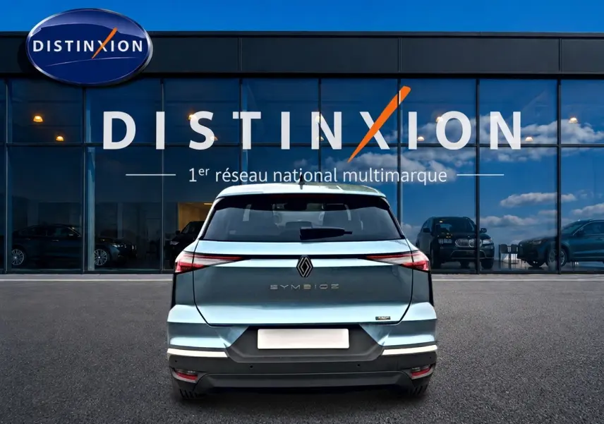 Vue arrière d'une Renault Symbioz bleu mercure avec feux LED et logo centré devant une vitrine Distinxion.