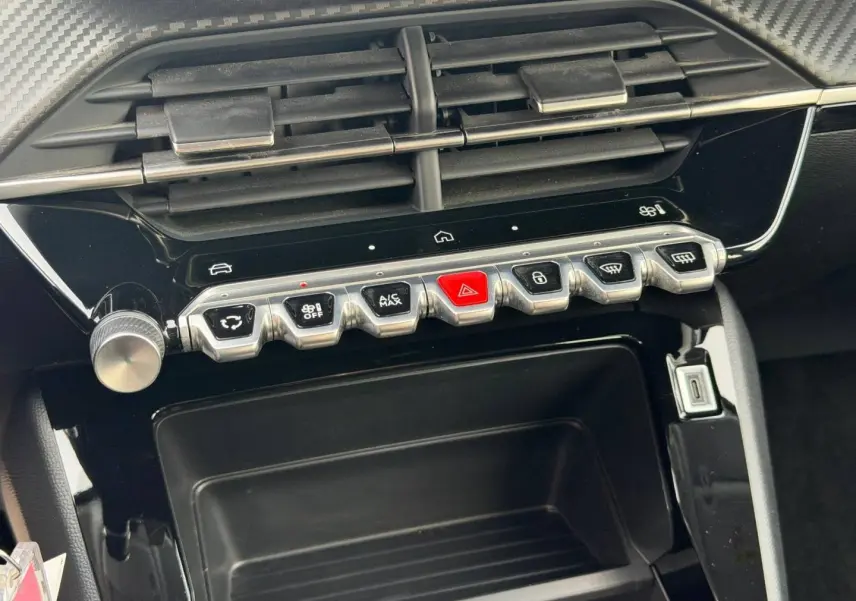 Vue rapprochée de la console centrale noire avec commandes piano et prise USB du Peugeot 208 blanc Okénite.