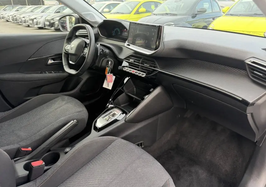 Intérieur avant droit de la Peugeot 208 1.2 Hybrid 110ch Style 2025 avec tableau de bord noir et écran tactile central.