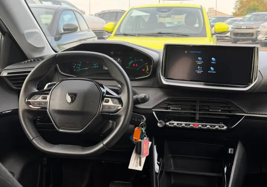 Intérieur Peugeot 208 2025 vu du poste de conduite, volant compact, tableau de bord numérique et écran tactile central.